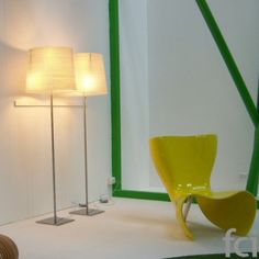 a yellow chair sitting in front of a mirror on top of a white floor next to a lamp