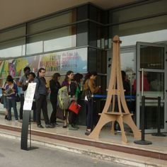 a group of people standing in front of a building with a wooden eiffel tower