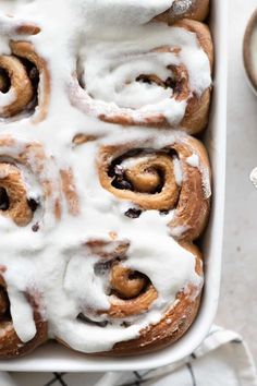 a pan filled with cinnamon rolls covered in icing