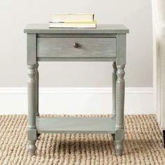 a small table with a book on top of it next to a chair and rug