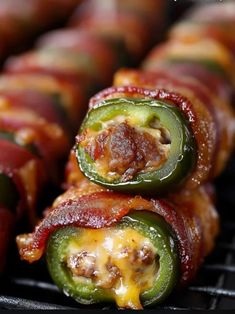 bacon wrapped jalapenos on a grill with melted cheese and pepperonis in the middle