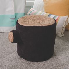 a tree stump sitting on the floor next to pillows