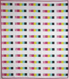 a white quilt with multicolored squares on it