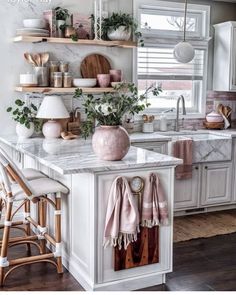 a kitchen filled with lots of white cabinets and counter top next to a window covered in plants