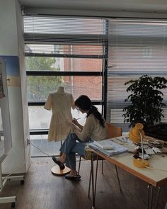 a woman sitting at a table working on a piece of clothing