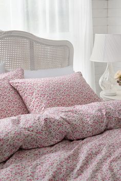 a bed with pink and white flowers on it next to a window in a bedroom