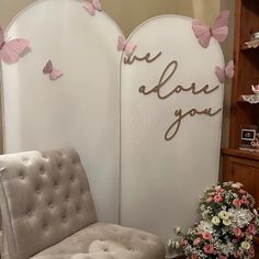 a white chair sitting next to a wall with pink butterflies on it's back