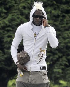 a man in white jacket and sunglasses holding a baseball glove while talking on a cell phone