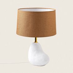 a table lamp with a brown shade on top of it and a light bulb attached to the base