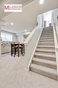 an empty living room with stairs leading up to the kitchen and dining area in the background