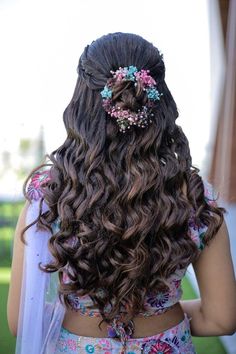 the back of a woman's head with long hair and flowers in her hair