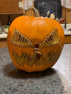 an orange pumpkin decorated with gold paint and skeleton teeth on a kitchen counter top next to a sink