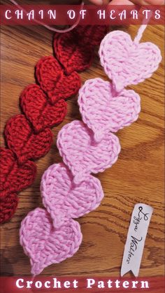 two crocheted hearts sitting on top of a wooden table