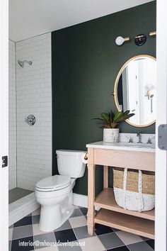 a white toilet sitting next to a sink in a bathroom under a large round mirror