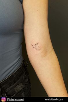 a woman's arm with a small leaf tattoo on the left side of her arm