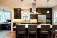 a kitchen with dark wood cabinets and marble counter tops, along with an island in the middle