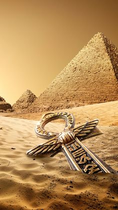 a cross in the desert with pyramids in the background