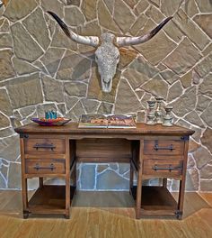 a wooden desk topped with two drawers and a cow skull on the wall behind it