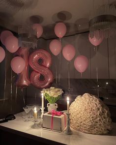 a table topped with balloons and candles next to a cake