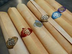 five different colored rings sitting on top of wooden sticks in a row, with the word monogram written on them