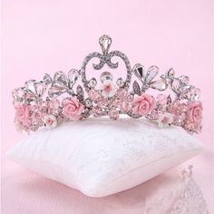 a tiara with pink flowers on it sitting on a pillow in front of a pink background