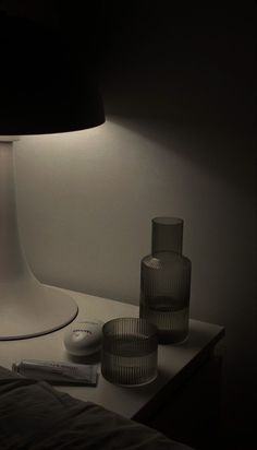 the lamp is next to two glasses and a remote control