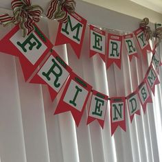 a red and green banner hanging from the side of a window next to white curtains