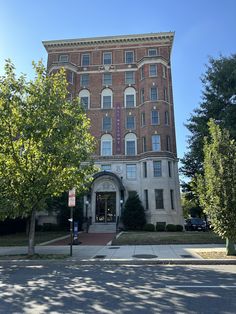 an old brick building on the corner of a street with trees in front of it