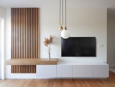 a flat screen tv mounted to the side of a wall next to a wooden shelf