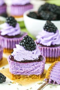 there are several cupcakes with purple frosting and blackberries on top,