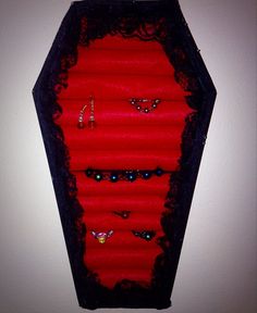 a red and black box with lots of jewels on the inside is sitting in front of a white wall