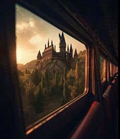 a castle seen through the window of a train at sunset or sunrise, with trees and mountains in the foreground