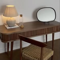 a wooden desk with a mirror and lamp next to it