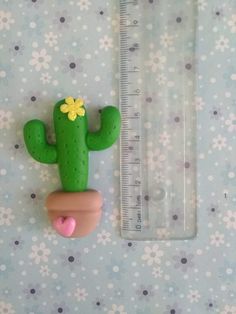 a green cactus with a yellow flower on it next to a measuring tape and plastic ruler