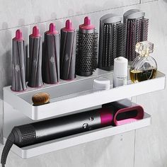 the shelf is holding many different types of hair brushes and blow dryers on it