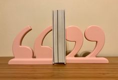 a pink bookend with two books on it sitting on top of a wooden table