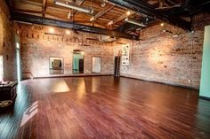 an empty room with hard wood floors and exposed brick walls