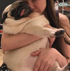 a woman holding a pug dog in her arms