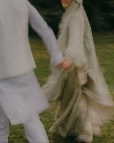 the bride and groom are walking through the grass