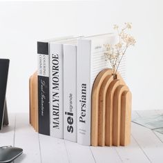 there is a bookend made out of wood and has four books on it next to a computer mouse