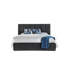 a bed with blue and white pillows on it's headboard next to a blanket