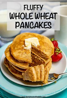 stack of fluffy whole wheat pancakes with butter on top and strawberries in the background