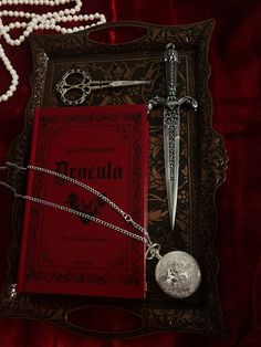 a red book with a chain and some scissors next to it on a velvet surface