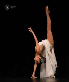 a woman is doing a handstand on the floor in front of a black background