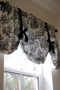 a window curtain with black and white flowers on the valance, hanging in front of a window