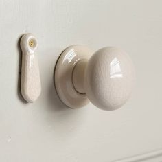 a white door knob with a long handle on the side of a wall next to a pair of scissors