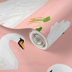 a pink and white wallpaper with swans on it's face, next to a roll of toilet paper