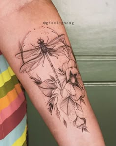 a woman's arm with a dragonfly and flowers tattoo on the left forearm