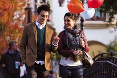 a man and woman walking down the street with balloons