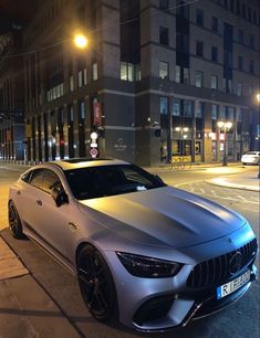 a silver car parked in front of a tall building on the side of a street